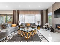 A stylish living room featuring couches, a fireplace, a glass coffee table and bright windows with decor at 11193 Mission Walk St, Parker, CO 80134