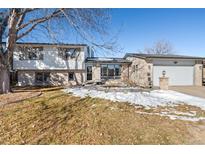 Ranch style home with mature trees and snow-covered lawn at 749 Poppy Dr, Brighton, CO 80601