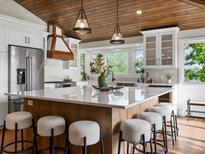 Bright kitchen boasts a large island with seating, modern appliances, and wood-paneled ceilings at 12196 W Belleview Dr, Littleton, CO 80127