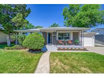 Charming brick home featuring a well-manicured lawn, inviting front porch with chairs, and tidy landscaping at 7011 Poplar St, Commerce City, CO 80022