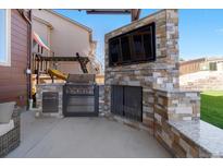 This outdoor kitchen features a built-in grill, fireplace, and mounted television for year-round enjoyment at 3745 Spanish Oaks Trl, Castle Rock, CO 80108