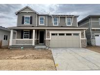 Two-story home featuring a large garage, covered porch, and stone detailing along the front of the house at 24718 E 40Th Ave, Aurora, CO 80019