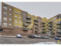 Multi-level apartment complex with brick facade, balconies and ample parking in a snowy scene at 9079 E Panorama Cir # 309, Englewood, CO 80112