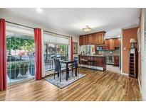 Inviting living room with a dining table, bar seating, wood cabinets, and a large window with balcony access at 1200 N Humboldt St # 101, Denver, CO 80218