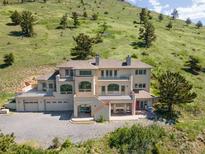 Stunning multi-story home nestled against a hillside with a multi-car garage and outdoor deck at 606 Sugarloaf Mountain Rd, Boulder, CO 80302