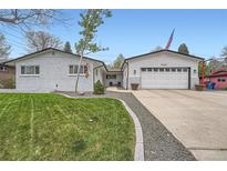 Charming home featuring a brick facade, well-manicured lawn, and an attached two-car garage at 1025 Zang St, Golden, CO 80401