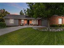 Charming brick home featuring a lush green lawn and a long driveway at dusk at 7440 Quail St, Arvada, CO 80005