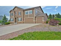 View of a multi-story house with a three-car garage and a well-maintained driveway with decorative rock at 735 Woodmoor Acres Dr, Monument, CO 80132