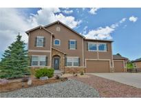Charming two-story home featuring stone accents, a three-car garage, and a landscaped front yard at 735 Woodmoor Acres Dr, Monument, CO 80132