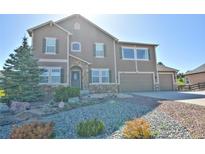 Two-story home with stone accents, lush landscaping, attached garage, and beautiful curb appeal at 735 Woodmoor Acres Dr, Monument, CO 80132