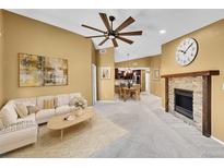 Bright living room featuring a fireplace, ceiling fan, and open floor plan to the kitchen and dining area at 8747 E Dry Creek Rd # 1623, Englewood, CO 80112