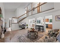 Inviting living room boasts a brick fireplace, stairs to a loft, and seamless flow to kitchen and dining area at 7507 Braun St, Arvada, CO 80005
