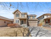 Charming two-story home featuring a stone facade, covered porch, and attached two car garage at 16643 E 101St Ave, Commerce City, CO 80022