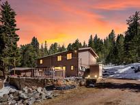 Charming two-story house featuring a deck, rock facade, and beautiful sunset sky at 28268 Shadow Mountain Dr, Conifer, CO 80433