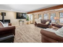 Inviting living room featuring hardwood floors, a cozy wood stove, and comfortable leather furniture at 28268 Shadow Mountain Dr, Conifer, CO 80433