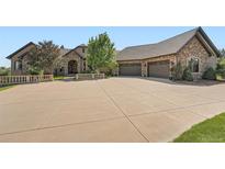Sprawling home featuring stone accents, large driveway, and three-car garage perfect for luxury living at 4725 Palmer Ridge Dr, Parker, CO 80134