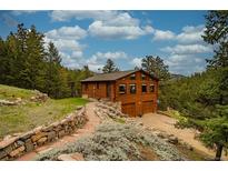 Charming wooden cabin exterior with a stone path and a two-car garage in a wooded setting at 310 Wendelyn Way, Boulder, CO 80302