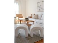 Bright living room featuring neutral tones, stylish white sofa, textured stools and modern accents at 2301 E Fremont Ave # W03, Centennial, CO 80122