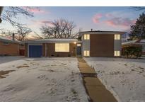 Brick ranch home with a blue door and snowy front yard at 12352 E 30Th Ave, Aurora, CO 80011