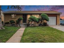 Charming brick home featuring a well-manicured lawn and mature landscaping at 7644 Wyandot St, Denver, CO 80221