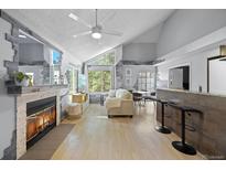 Bright living room featuring a fireplace, bar seating, and large windows at 13824 E Lehigh Ave # B, Aurora, CO 80014