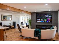 Bright living room featuring hardwood floors, modern fireplace, and a large screen tv at 8950 W 26Th, Lakewood, CO 80215
