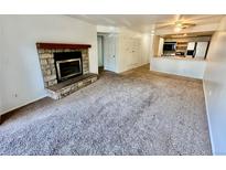 Inviting living room featuring a stone fireplace and seamless flow into the adjacent kitchen at 16001 E Alaska Pl # 7, Aurora, CO 80017