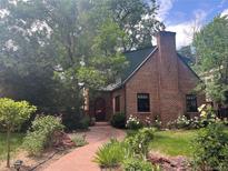 Charming brick home with a lush garden, stone walkway, chimney and arched entry at 357 Birch St, Denver, CO 80220