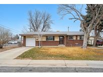 Charming brick and siding home featuring a driveway and a well-maintained front lawn in a quiet neighborhood at 3261 Kassler Pl, Westminster, CO 80031