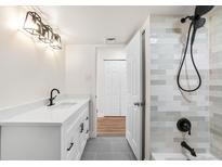 Modern bathroom featuring white vanity, grey tile floors, and walk-in shower with black fixtures at 3315 S Monaco St # B, Denver, CO 80222