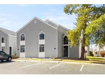 Two story condo with gray siding, white trim, and large tree in the foreground at 3315 S Monaco St # B, Denver, CO 80222