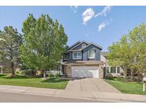 Charming two-story home with blue siding, stone accents, mature landscaping, and a well-manicured front lawn at 10610 Winterflower Way, Parker, CO 80134