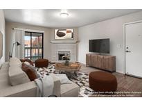 Bright living room featuring a fireplace, balcony access, modern furniture, and wood flooring at 8335 Fairmount Dr # 9-206, Denver, CO 80247