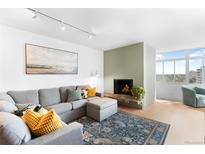 Bright living room features a charming fireplace, comfortable gray sectional and stylish decor at 1313 N Williams St # 1003, Denver, CO 80218