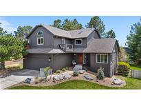 Beautiful two-story home with gray siding, brick accents, mature landscaping, and a well-maintained front yard at 6275 Ponderosa Way, Parker, CO 80134