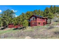 Charming red two-story home with lots of windows and solar panels nestled among trees at 548 Coughlin Meadows Rd, Boulder, CO 80302