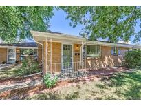 Charming brick home featuring a covered front porch and mature trees at 5563 Newland Way, Arvada, CO 80002