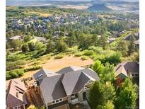 Stunning aerial view of a luxury home surrounded by trees and overlooking a beautiful mountain range and neighborhood at 1975 Wild Star Way, Castle Rock, CO 80104