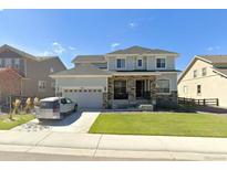 Charming two-story home with stone accents, a well-manicured lawn, and an attached two-car garage at 14221 Ivanhoe St, Thornton, CO 80602