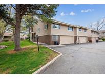 Charming townhome featuring a brick facade and attached garage with a well-maintained lawn and mature tree at 6917 E Girard Ave, Denver, CO 80224