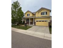 Charming yellow two-story home featuring a spacious driveway and well-manicured lawn at 4970 Laurelglen Ln, Highlands Ranch, CO 80130