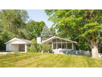 Beautiful gray home with mature trees and a well-manicured lawn offering great curb appeal at 950 Everett St, Lakewood, CO 80215