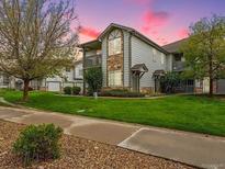 Attractive two-story condo boasts a charming stone and siding exterior with balcony, set against a green lawn and trees at 3262 E 103Rd Dr # 1806, Thornton, CO 80229