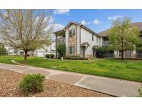 Attractive condo building with stone accents, a well-manicured lawn, and mature shade trees at 3262 E 103Rd Dr # 1806, Thornton, CO 80229