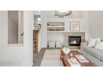 Cozy living room with a fireplace, open shelving, decor, and staircase access in a bright, airy interior at 9369 Longs Peak Dr, Commerce City, CO 80640