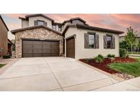 Beautiful home featuring a stone facade, brown trim and a spacious driveway and 3-car garage at 15160 W Iliff Pl, Lakewood, CO 80228
