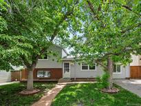 Charming home featuring a brick and siding exterior and mature trees along the front yard and brick walkway at 4858 S Quintero Cir, Aurora, CO 80015