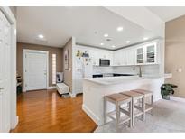 Bright kitchen with stainless appliances, white cabinetry and an island with bar seating at 6000 W Floyd Ave # 214, Denver, CO 80227