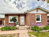 Charming brick home featuring a landscaped front yard with purple irises and a cozy front entrance at 1965 Havana St, Aurora, CO 80010