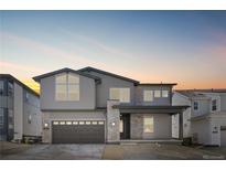 Beautiful two-story home with gray siding, stone accents, a covered porch and a two car garage under a colorful sky at 6633 Bridlespur St, Castle Pines, CO 80108